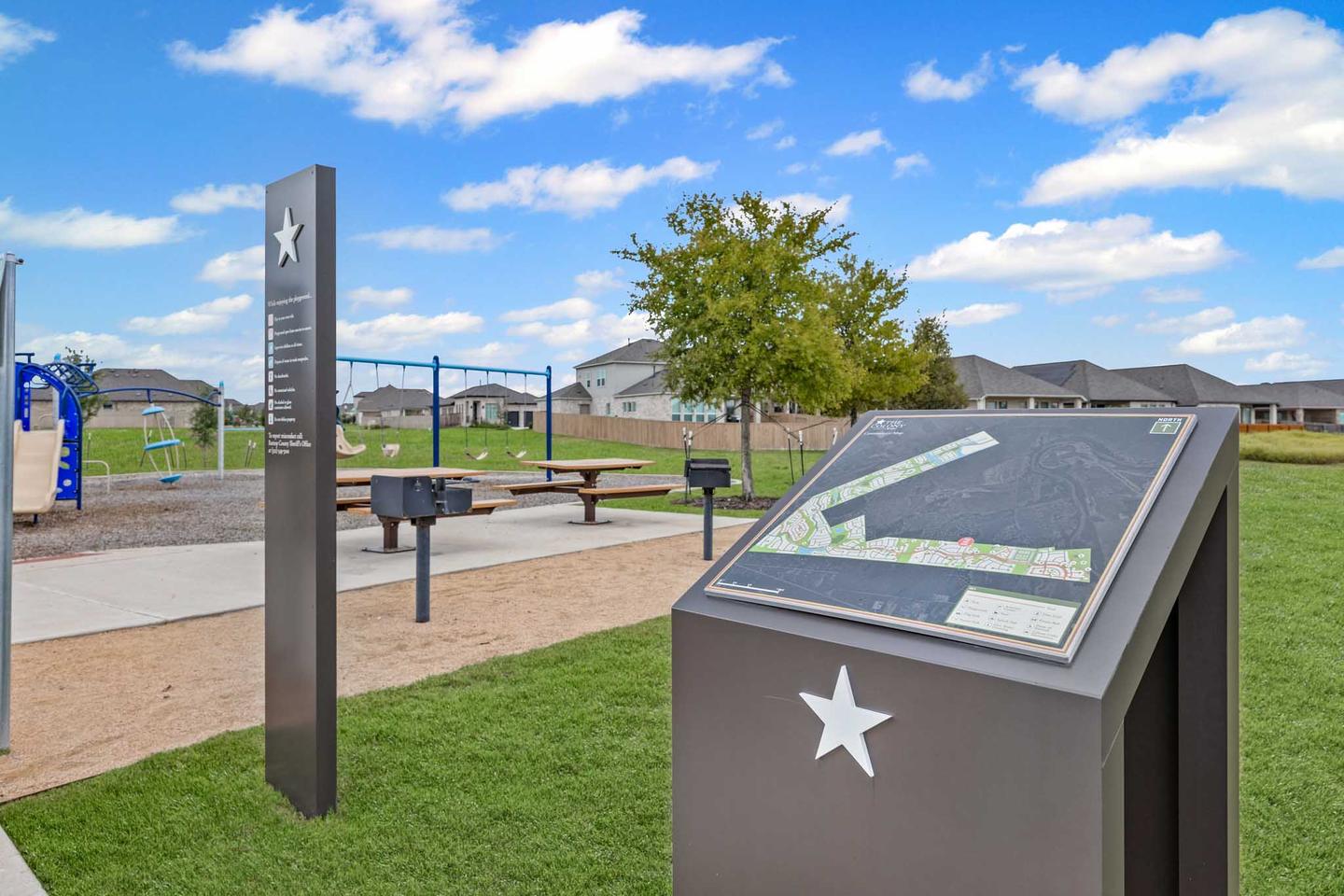 Community park in Bastrop with a paved path, an interpretive marker and open lawn