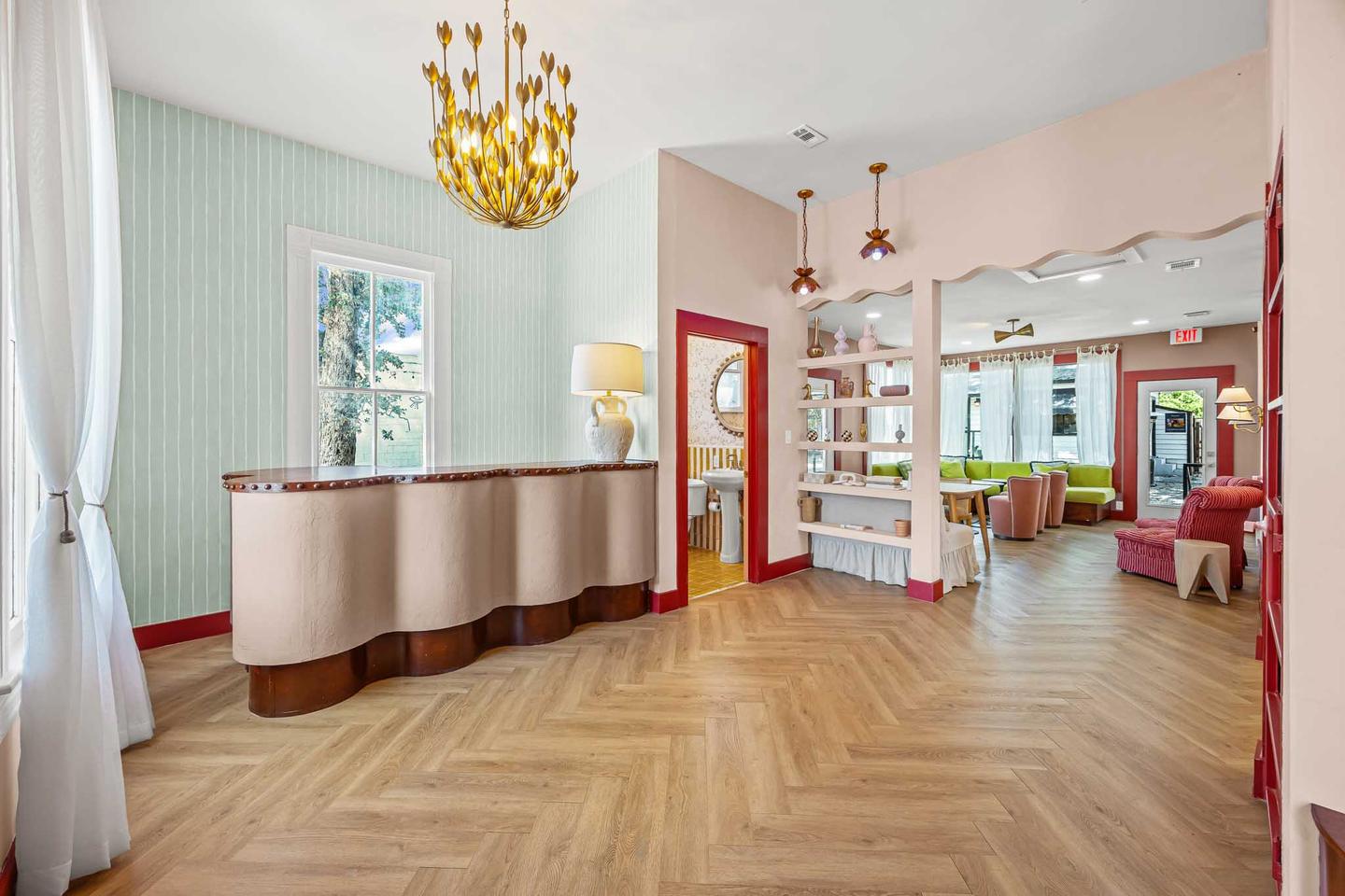 Leasing office lounge with a green sectional, pink armchairs and tall windows
