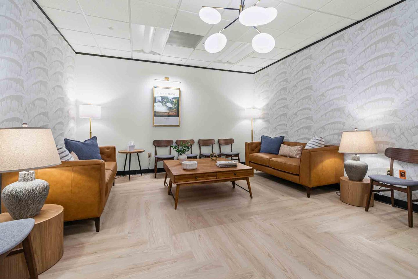 Office lounge with tan leather sofas, side tables and a wall of glass behind