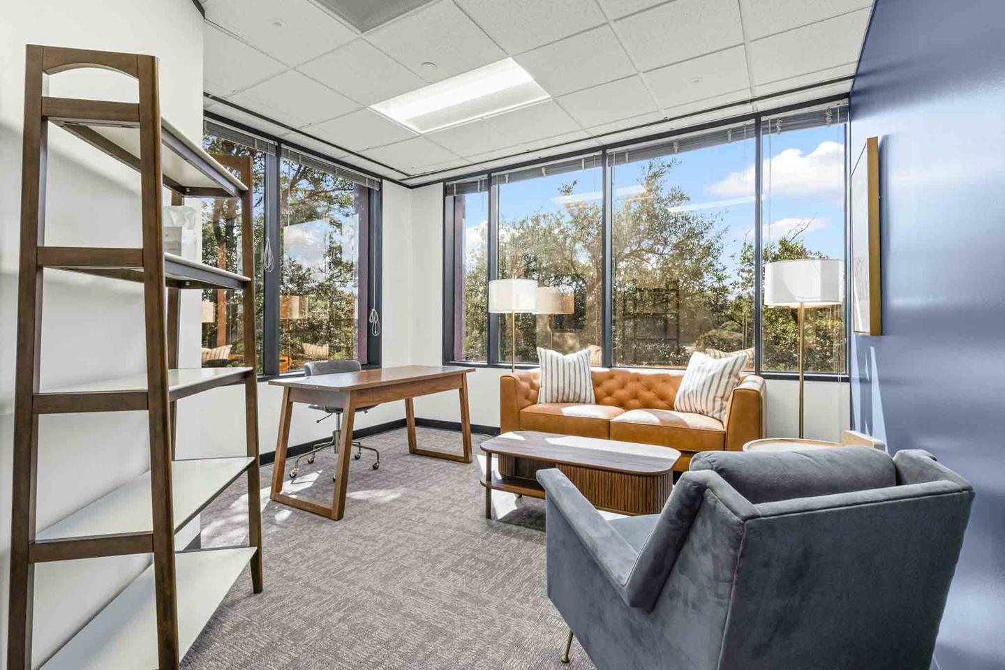 Office suite in Austin with a desk, a sofa and floor to ceiling windows on two sides