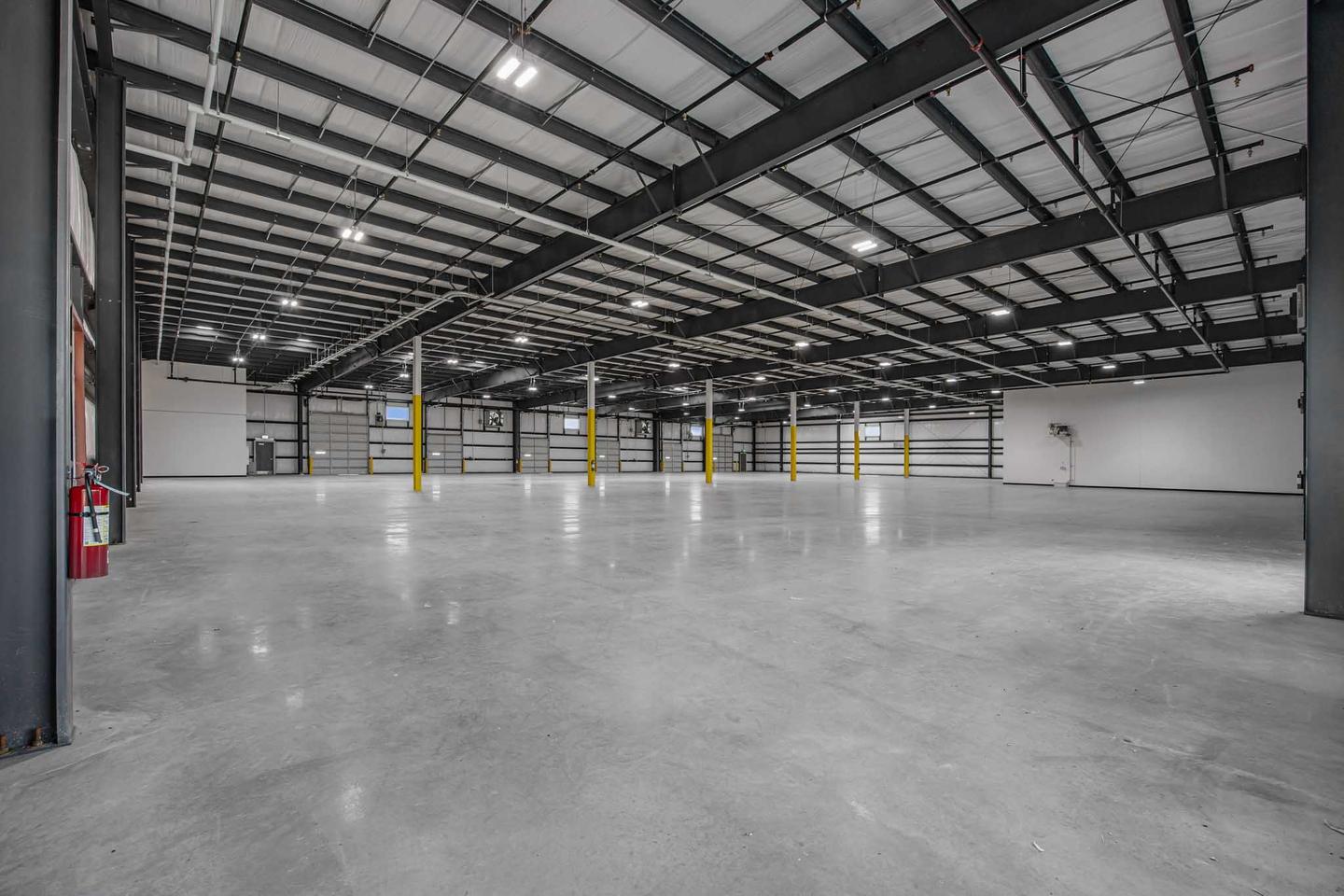 Empty warehouse interior in East Austin with a sealed concrete floor and exposed steel roof structure