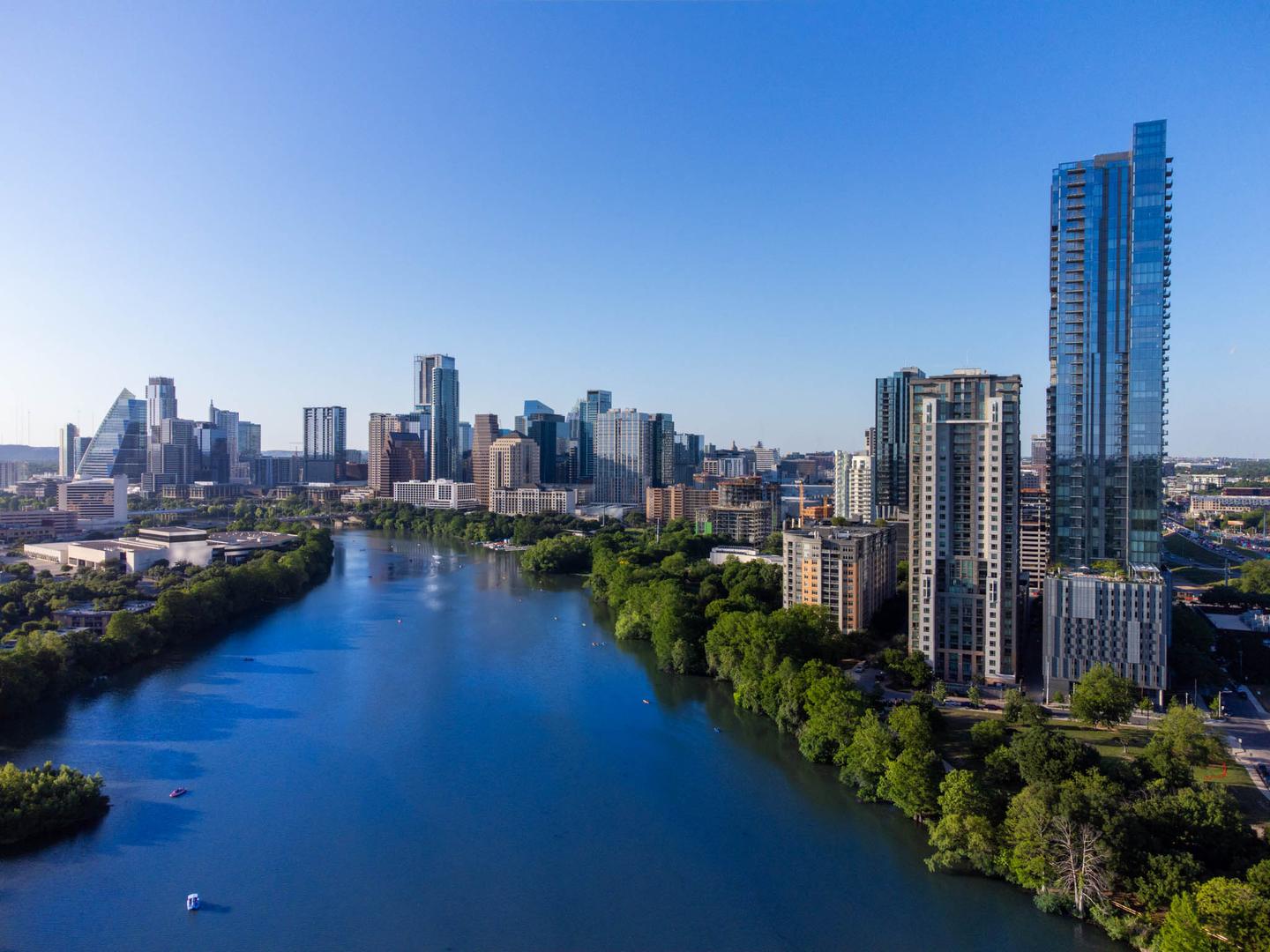 Aerial view of downtown Austin rising above the Colorado River on a clear day