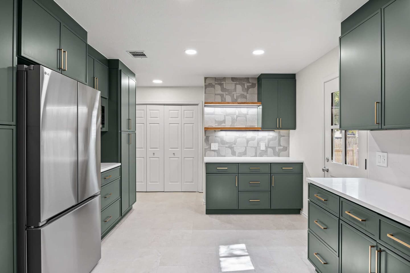 Renovated kitchen in South Austin with deep green cabinetry and stainless appliances