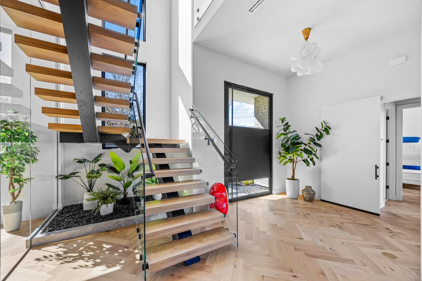 Entry hall with herringbone flooring running toward a planted courtyard at the far end