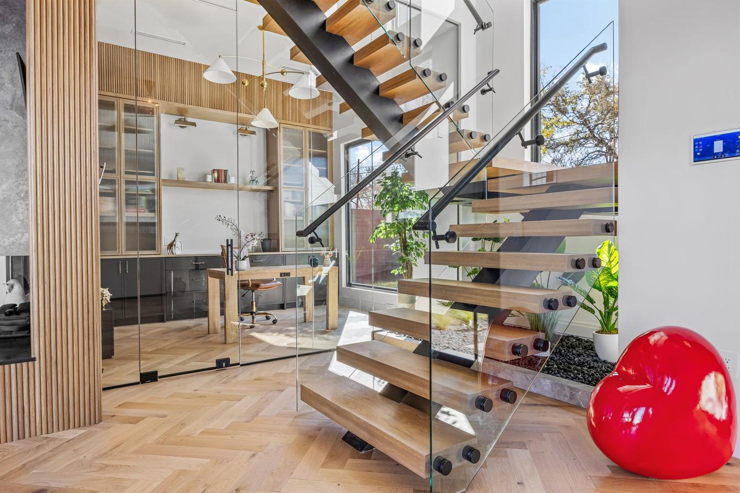 The open stair seen from the living room, with glazing on two sides and planting beyond