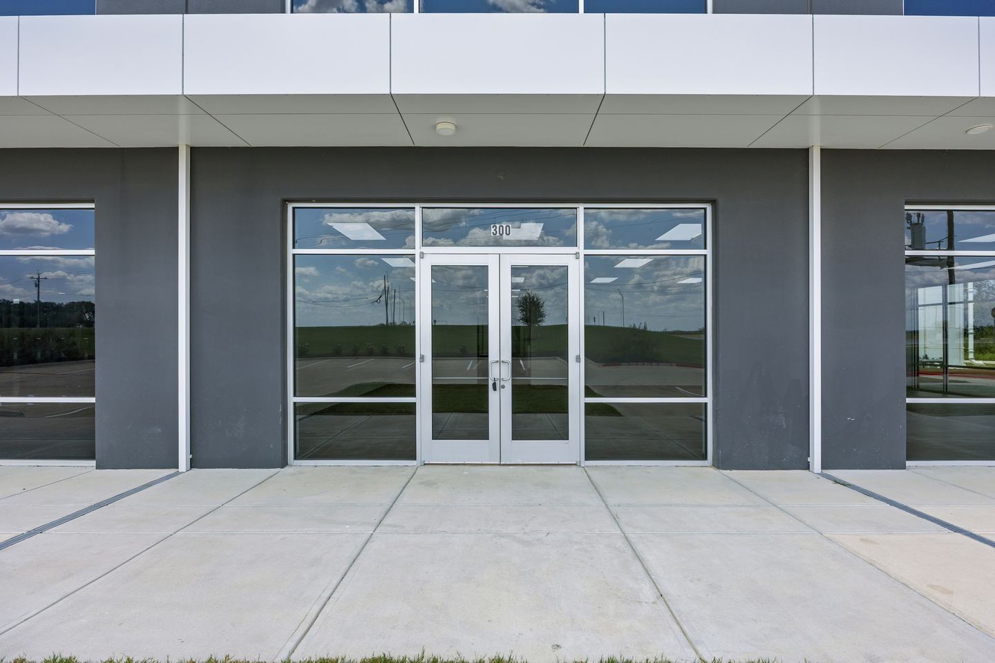 Glazed double door entrance set in a dark gray panel with a concrete apron