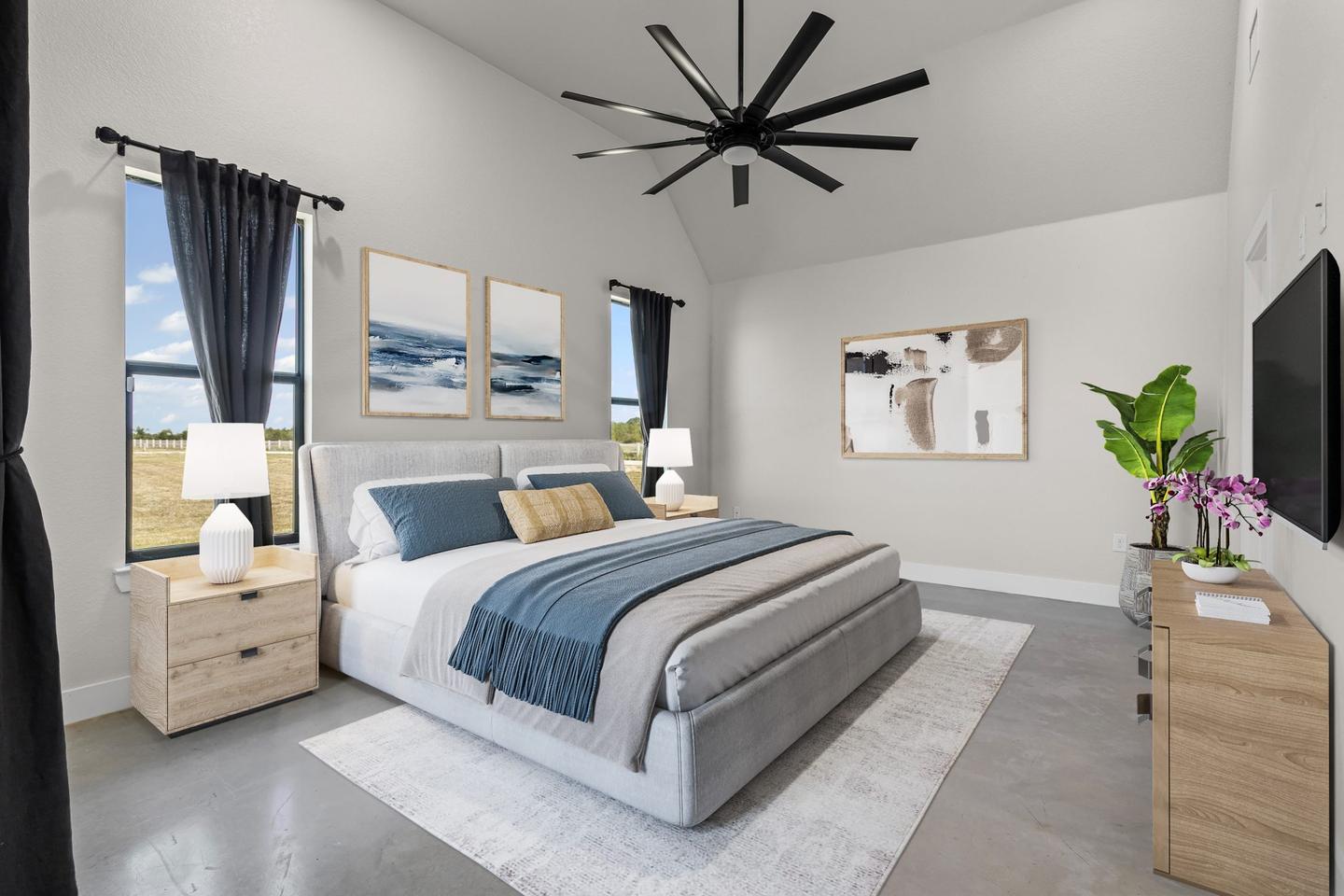 Primary bedroom staged with a made bed, timber side tables, lamps and framed art