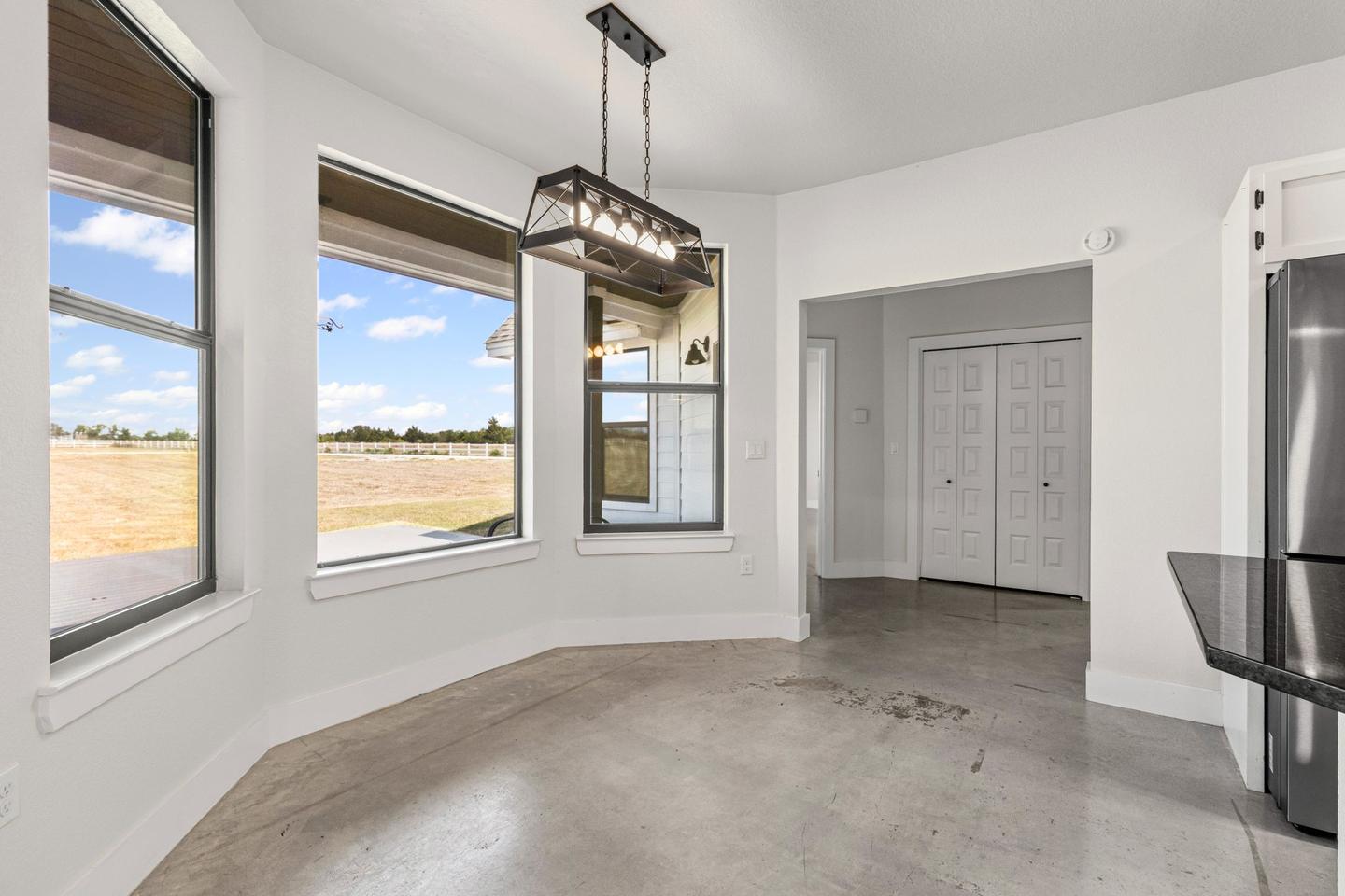 The same dining area empty, with a bay of windows looking out over open fields