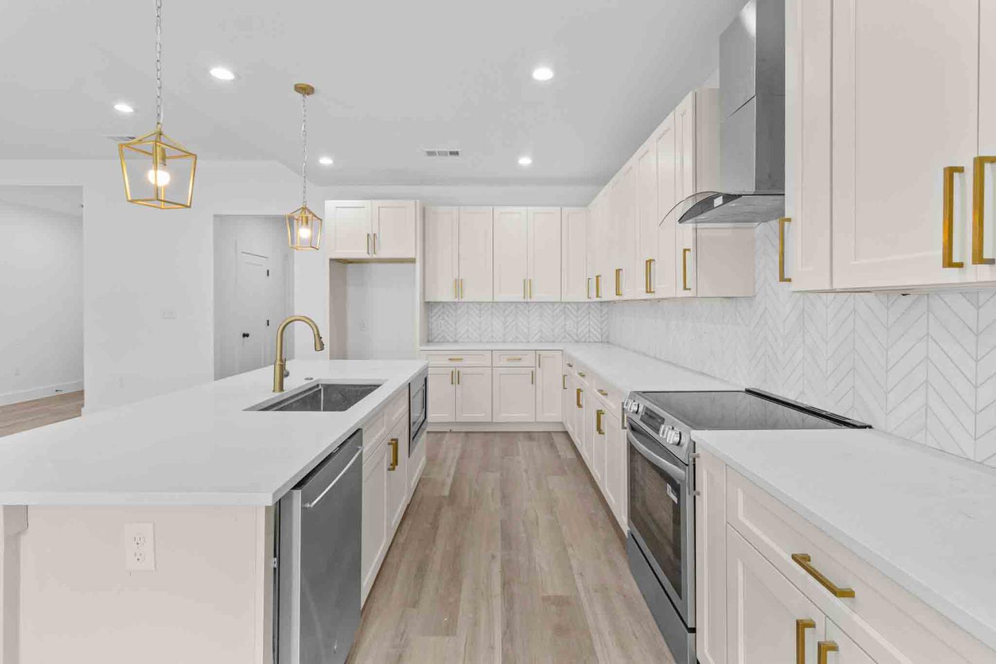 Kitchen in a Bastrop home with white cabinetry, gold hardware and a run of countertop
