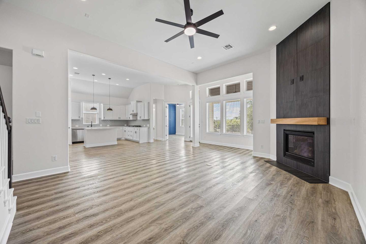 Vacant living room in Dripping Springs with a fireplace, tall windows and pale flooring