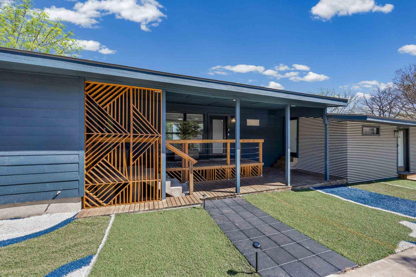 Navy mid century modern home in Austin with a slatted wood screen over the carport