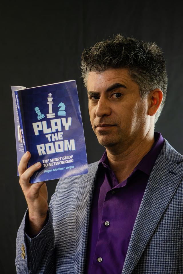 Branded headshot of a man in a gray blazer and purple shirt against a black backdrop