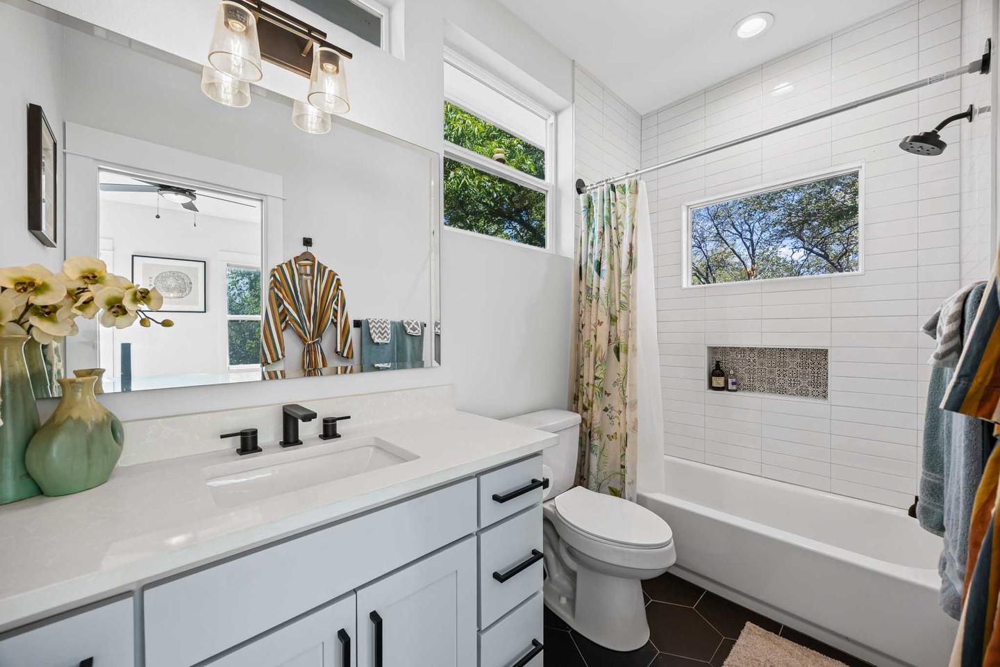Bathroom in Round Rock with a white vanity, a tiled tub surround and a window