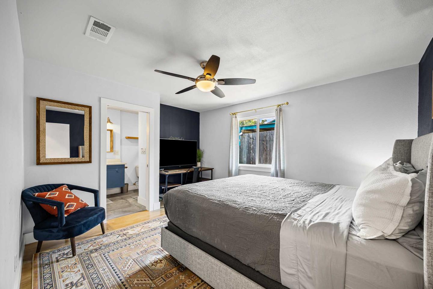 Short term rental bedroom in East Austin with a navy accent chair and a wall mounted television