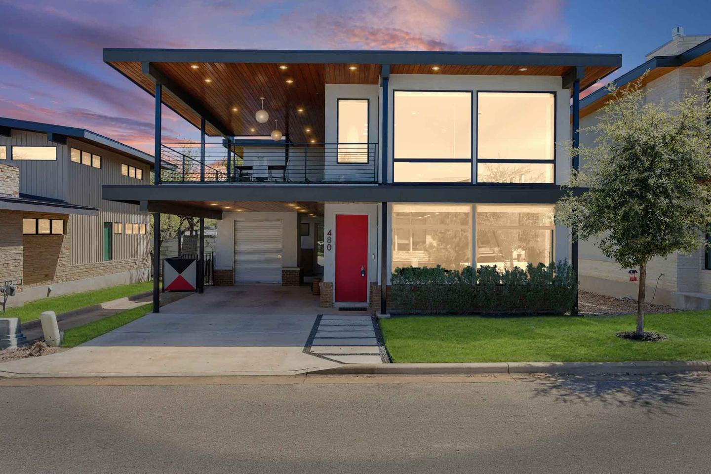 Modern two story home in North Austin at dusk with the glass frontage lit from inside
