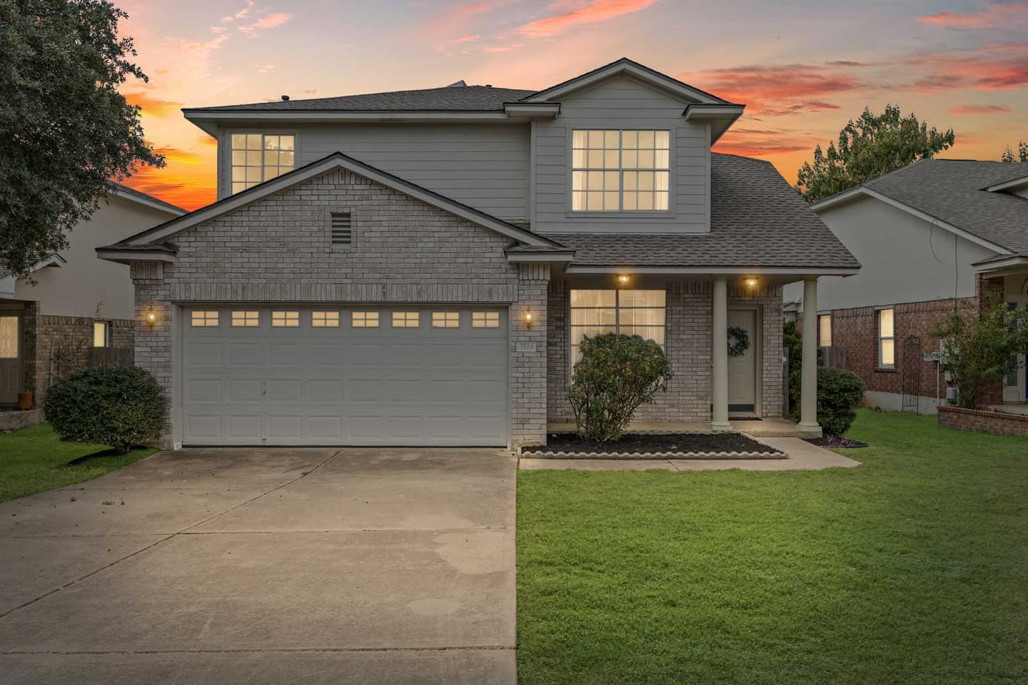 Round Rock home exterior at dusk with warm interior lights glowing through the windows